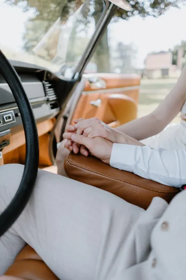 Händchen haltende Paare in einem Oldtimer mit einem natürlichen Hintergrund.